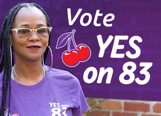 Picture of middle aged Black woman with long dreadlocks, wearing glasses and a purple shirt. Text is Vote Yes on 83 and a cartoon image of 2 cherries